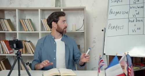 Männlicher Englischlehrer nimmt Videoblog in der Nähe des Schreibtisches auf
