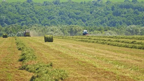 Rundballen auf dem Feld und Landmaschinen, die im Freien arbeiten.