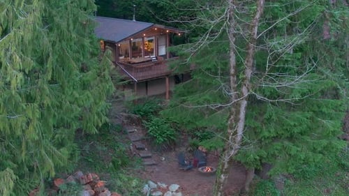 Serene Evening at a Wooden Riverside House With a Crackling Bonfire in the Forest