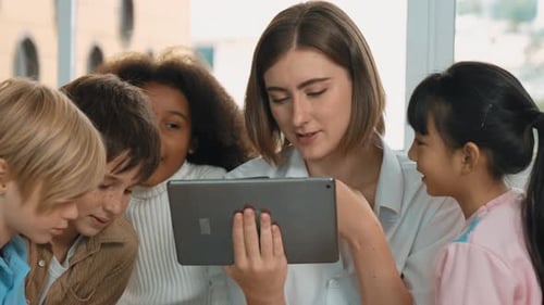 Children and Teacher Looking at Tablet in Classroom