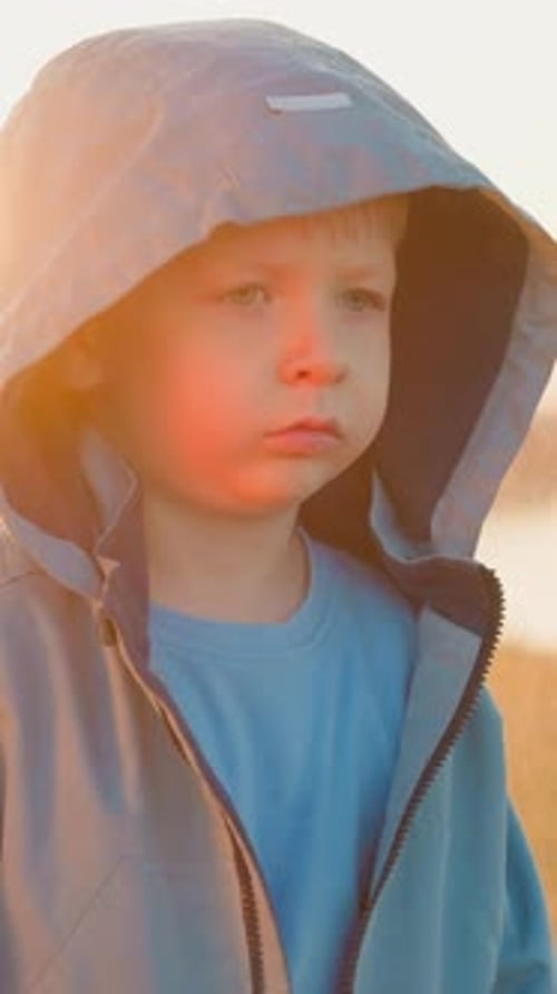Pensive Young Boy in Golden Light Wearing Hood