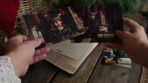Las manos revisan fotografías navideñas impresas para un álbum familiar