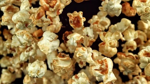 Popcorn falling in slow motion on dark background