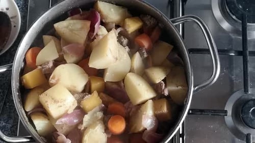 Top down view preparation of steaming stirring stew pot cooking on kitchen stove