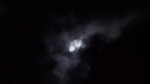 Schwarze Wolken schweben nachts sanft über den Vollmond