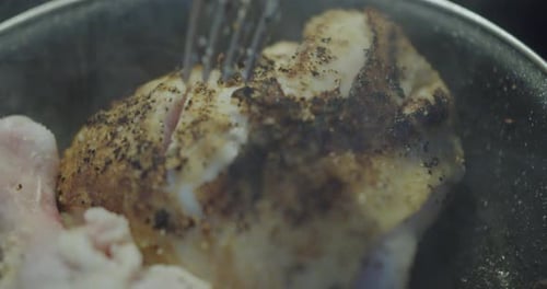 Chicken dam cooking in a black frying pan with oil and smoking. 4K