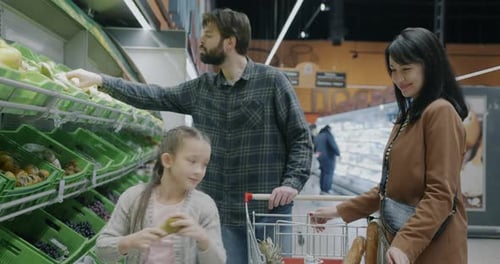 Slow Motion of Happy Family Mother Father and Daughter Choosing Fruit Buying Products in Supermarket