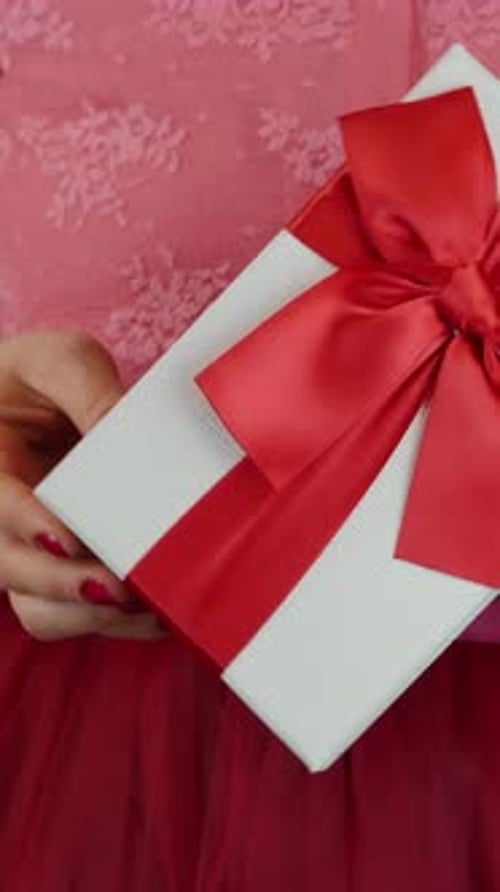 Gift Wrapped with Red Bow Held in Hands