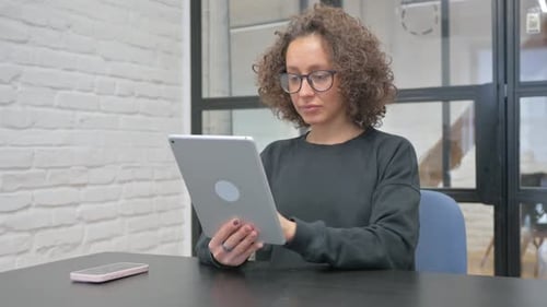Woman Using Tablet at Desk in Bright Office