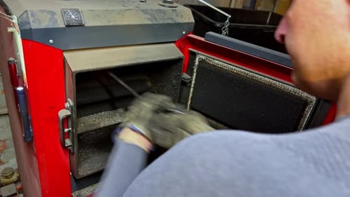 Technician cleaning retention sections in a wood heating boiler with metal brush