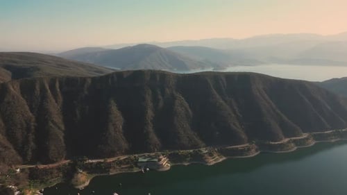 Aerial drone flying over a lake, water dam, with mountains at sunrise. Beautifull dreamy landscape.