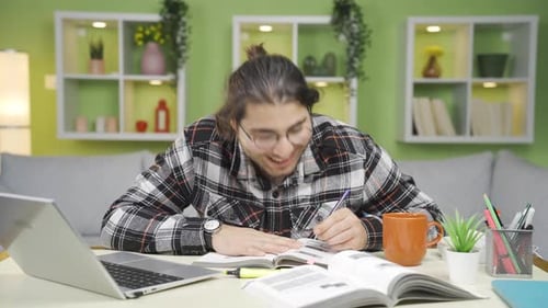 Young Adult Studying At Desk with Laptop and Books