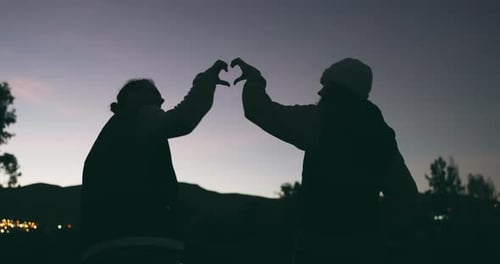 Silhouetted Figures Create Heart Shape at Sunset