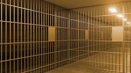 Empty jail cell with metal bars and artificial light