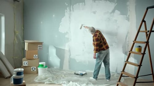 Man Painting Wall with Roller in Interior Space