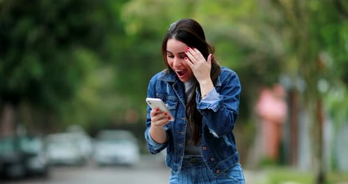 Happy Woman Reacts to Phone News Outdoors