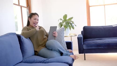 Woman Using Tablet, Relaxing on Couch in Home
