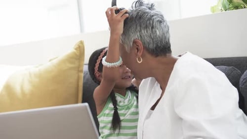 Grandmother and Granddaughter Using Computer With Headphones