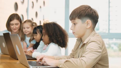 Smart boy playing laptop with multicultural friend learning prompt. Erudition.