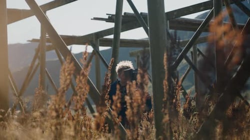 Man Filming with Camera in Rural Landscape