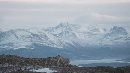 Zeitraffer der schneebedeckten norwegischen Berge, vorbeiziehende Wolken über einer wunderschönen malerischen Aussicht, während die Sonne langsam untergeht