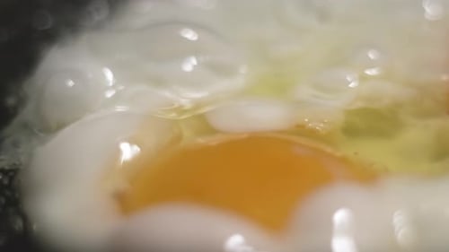 Fried Eggs Sizzling in a Pan on the Stove