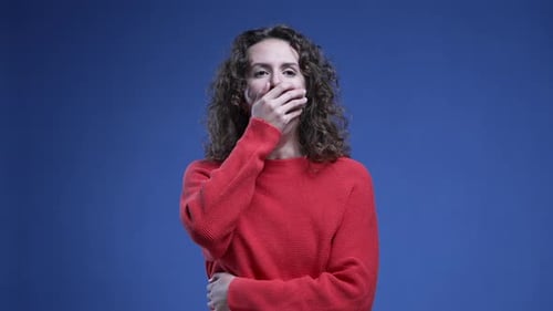 Femme fatiguée bâillant, couvrant la bouche avec la main, ressentant de la fatigue et de l'ennui debout sur fond bleu