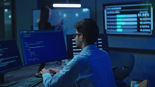 Male Developer Working At Computer With Data Screens
