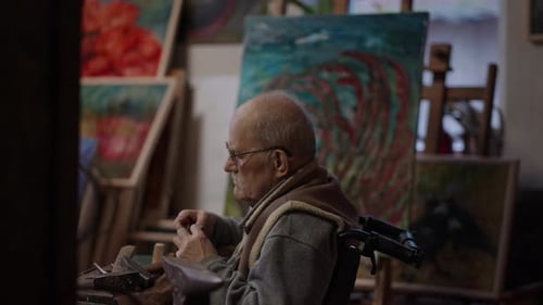 Senior Elderly Master Jeweler in Wheelchair Works in a Workshop