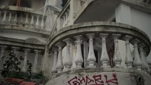 Old abandoned building covered in graffiti on balcony and walls, cinematic view