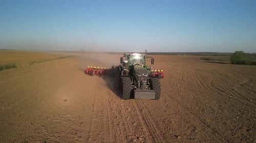 Green tractor works on the field sowing sunflower. Tractor planting corn in Ukraine