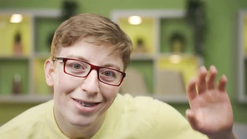 Close-up fun young man waving while looking at camera.