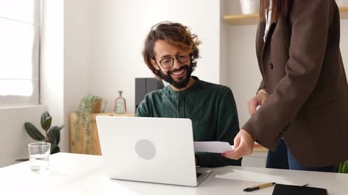 Professional Man Receives Documents from Coworker at Desk