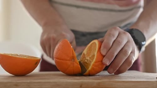 Man Slicing an Orange on Cutting Board