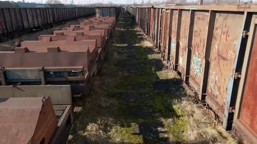 Flying between old rusted wagon trains in an abandoned train deposit