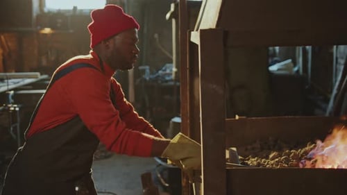 Craftsman Forging Metal in Dark Workshop