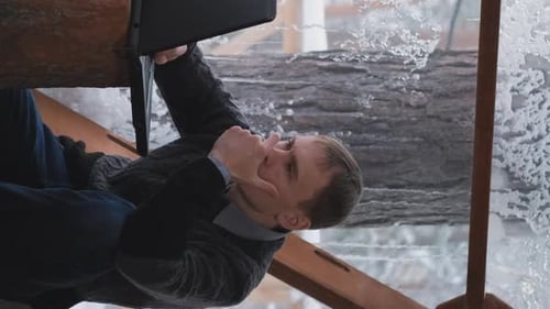 Young Man Using Laptop in Log Cabin Winter