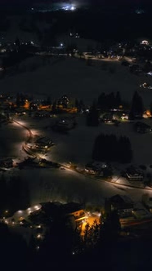 Aerial drone view of the buildings in the Cortina d'Ampezzo town in the Dolomites, Italy at night. V