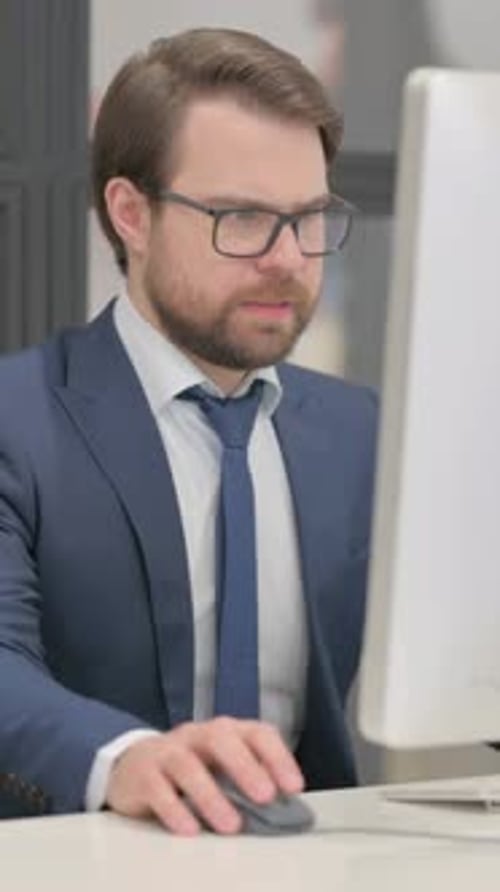 Serious Man Working on Computer in Office Setting