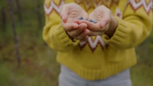 Young Hiker in Warm Sweater Shows Collected Blueberries