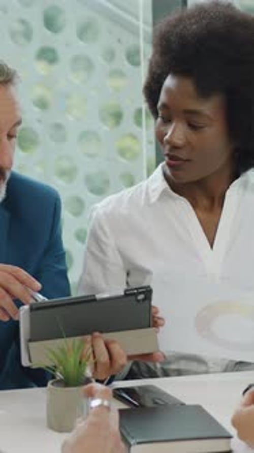 Business Professionals Discussing Charts and Tablet in Office