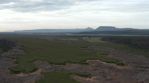 Flying away from Asbyrgi canyon above Eyjan rock formation in Iceland, cloudy
