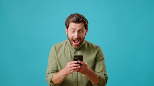 Young Man Exclaims in Surprise Looking at Smartphone Screen