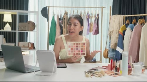 Asia lady blogger looking at camera recording swatch apply eyeshadow palette on skin show review.