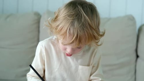 Young Child Explains Something While Drawing at Home