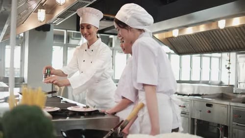 Female chef demonstrates to intern student girls in cooking class kitchen.