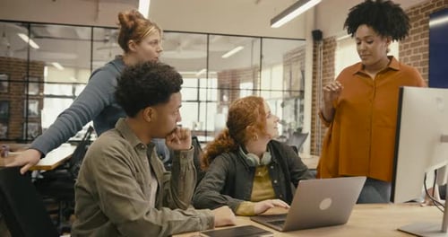 Group of Young Adult Business People Meeting in Creative Office Discussing Ideas around Computer