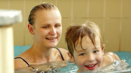 Happy boy and his mother swimming in the pool