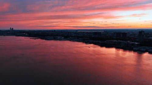 Pink sky reflecting in the waterscape of the river. Fantastic view of metropolis at dusk. Top view.