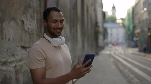 Portrait of the African American Man Looking at the Camera Holding the Mobile Phone Wearing